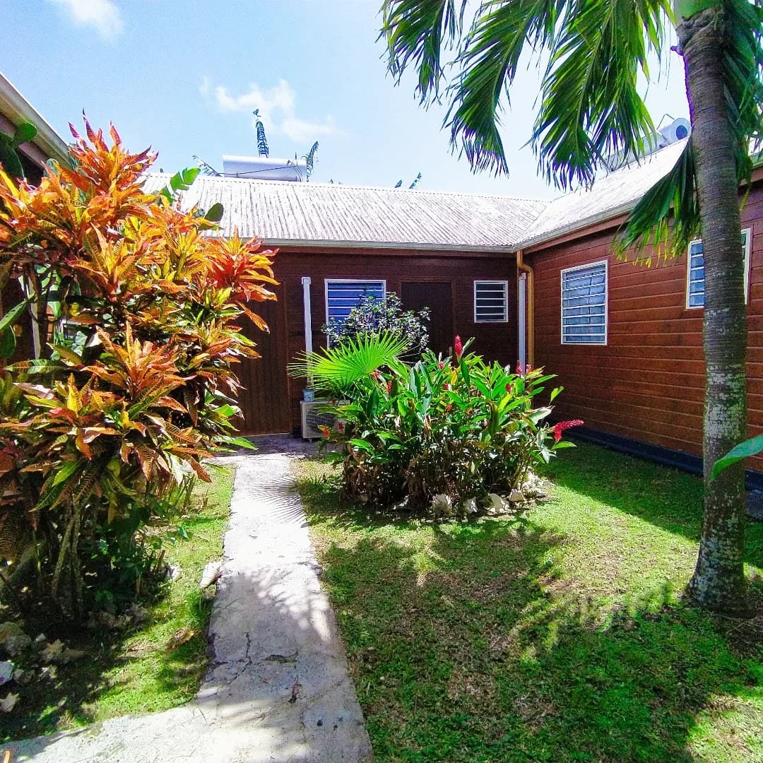 Le gîte Gwada Dream entouré de fleurs tropicales et de palmiers
