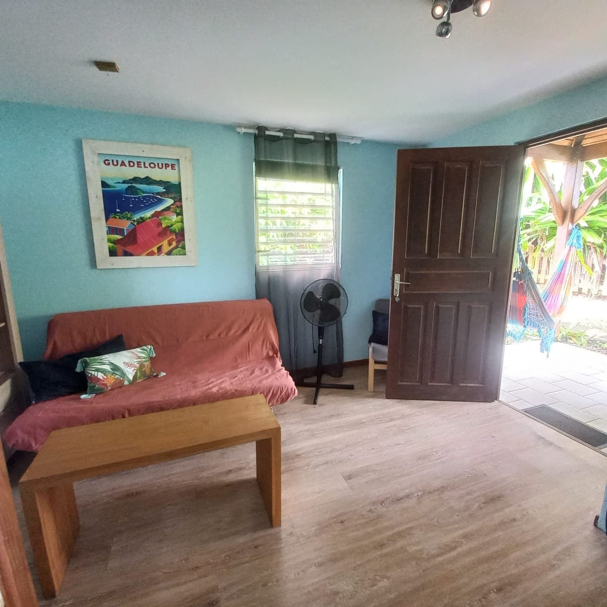 Salon aux murs turquoise avec futon rouge