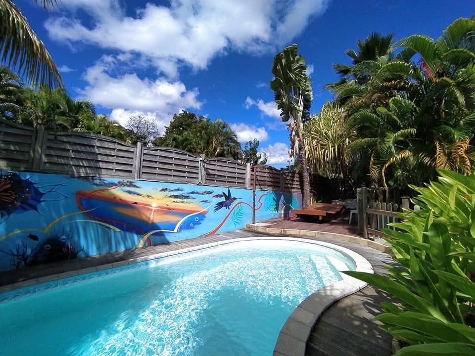 Espace piscine au sel avec sa fresque de poissons et les palmiers du jardin